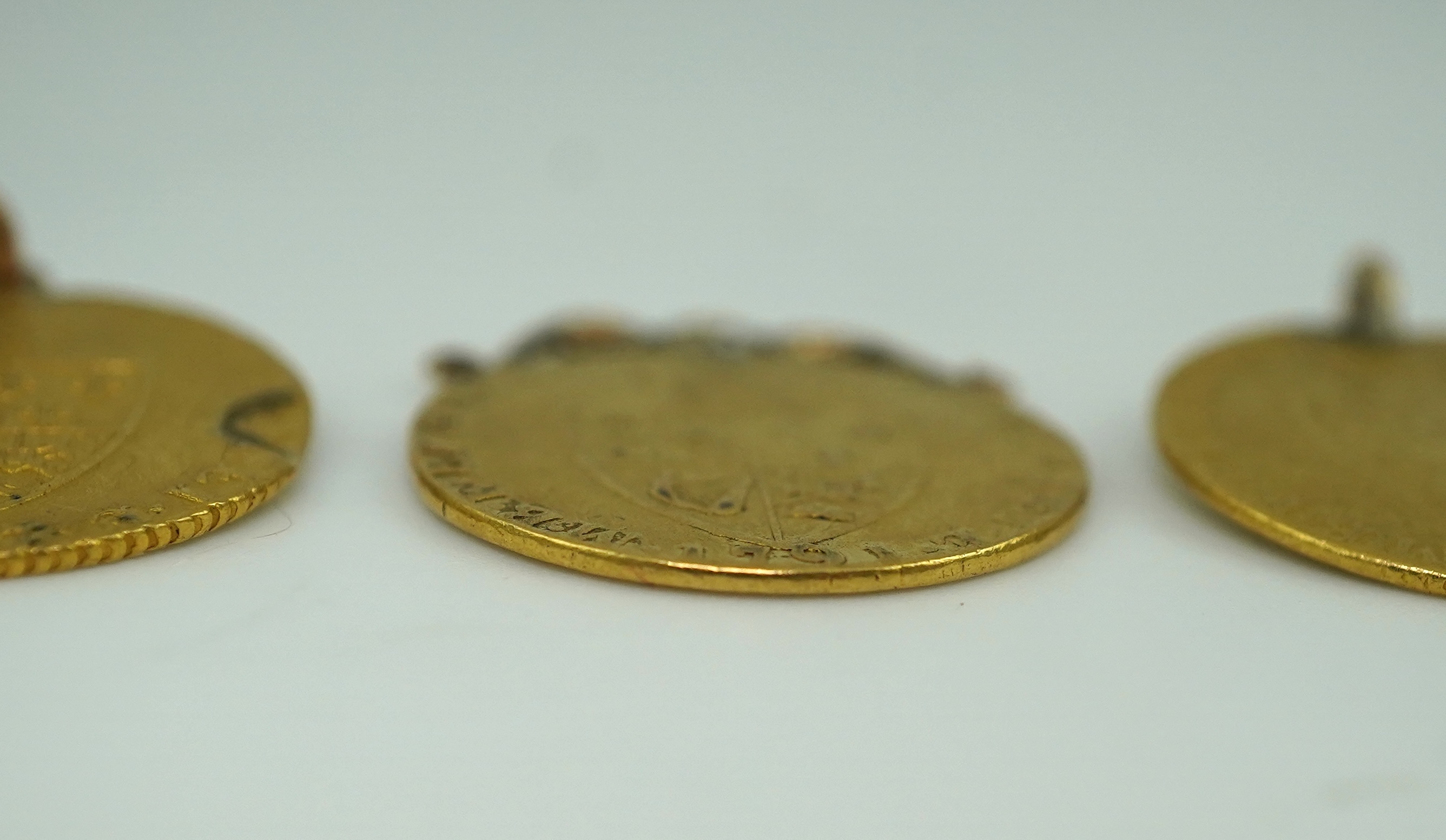 Three George III gold spade guinea coin pendants, late 18th/early 19th century and later